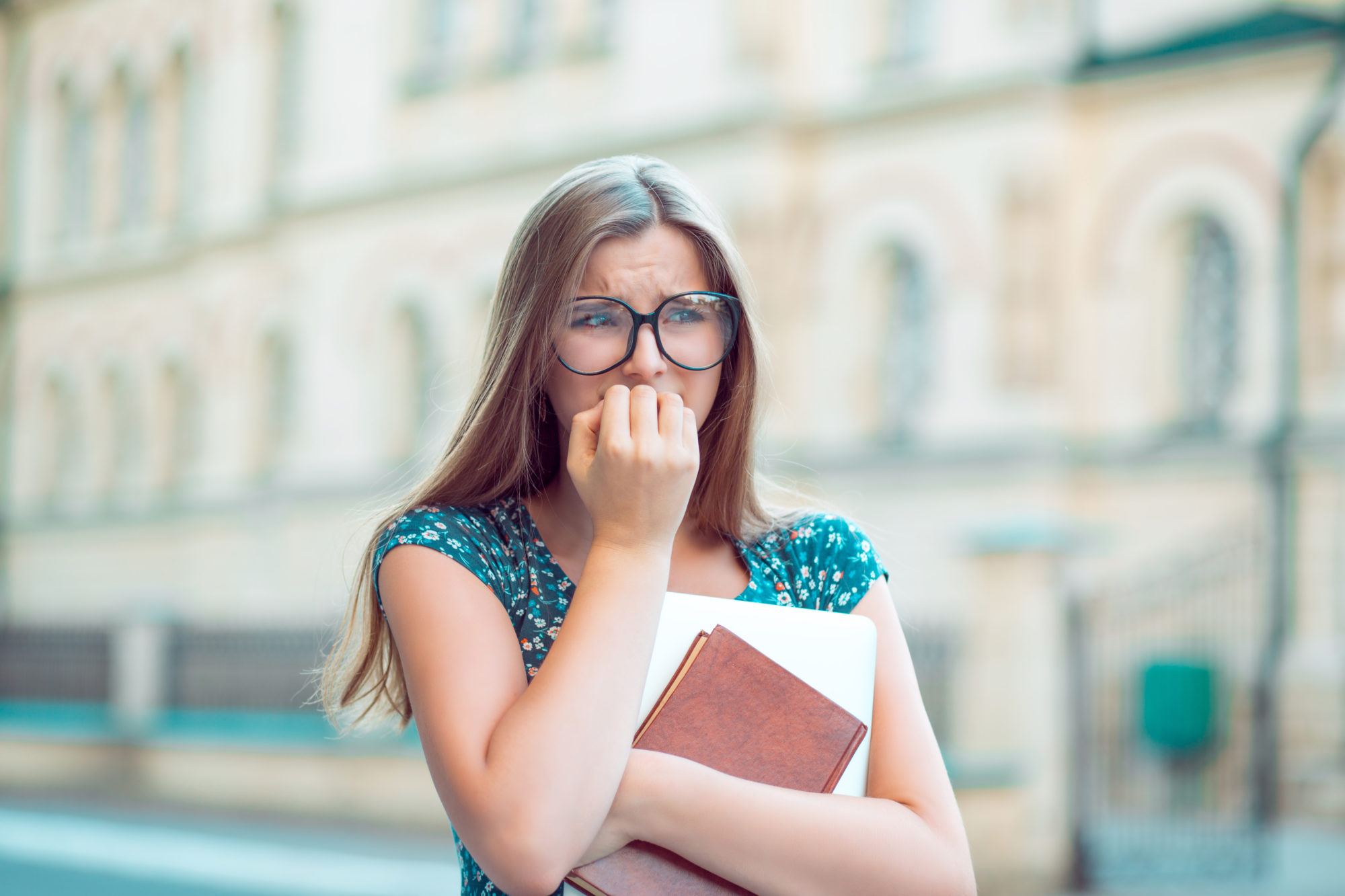 Student stressed young woman biting fingernails looking away anxiously